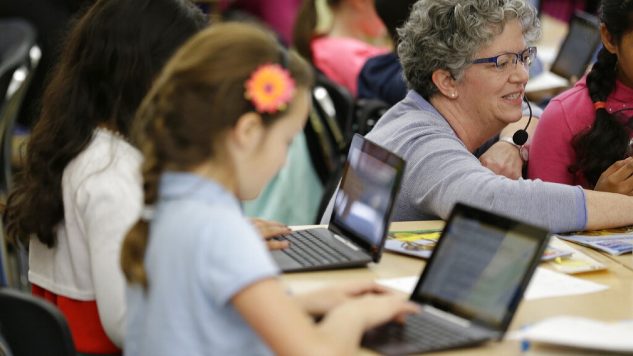Teacher assists fourth graders using Google docs to complete an exercise.
