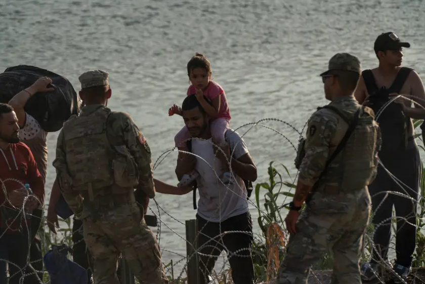 National Guard members tell migrants that they cannot cross the concertina wire barrier and must to walk to another area to surrender to authorities in Eagle Pass on July 29, 2023.