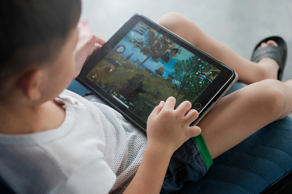 Stock image of a young child playing a game on a tablet.