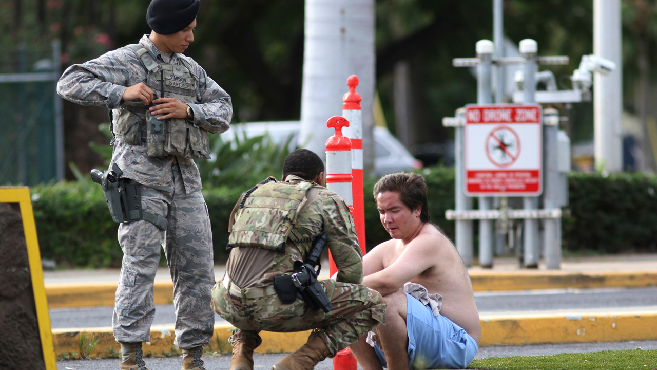 Security forces attend to an unidentified male outside the main gate at Joint Base Pearl Harbor-Hickam, Wednesday, Dec. 4, 2019, in Hawaii, following a shooting. 