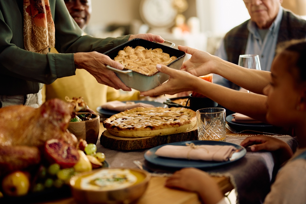 Close up of senior woman serving food to her family while celebrating Thanksgiving at home. 