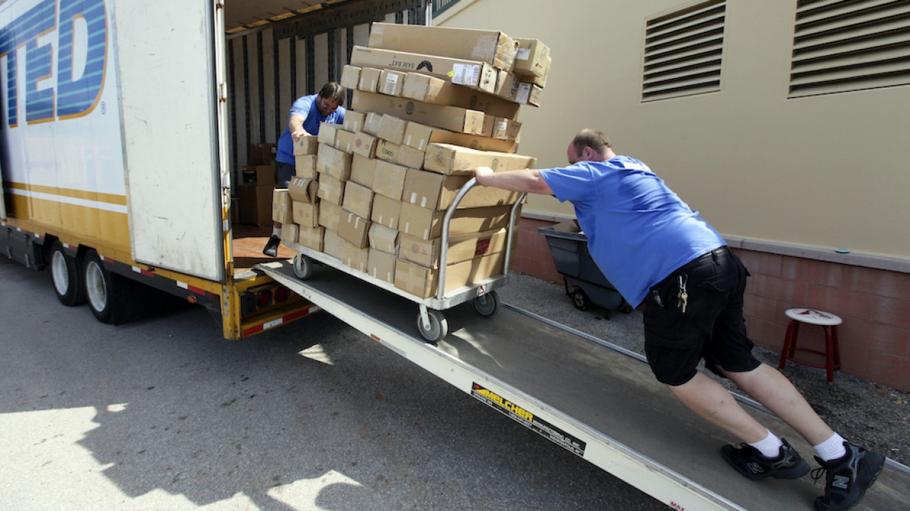 Movers roll boxes containing baseball bats belonging to members of the St. Louis Cardinals onto a moving truck.