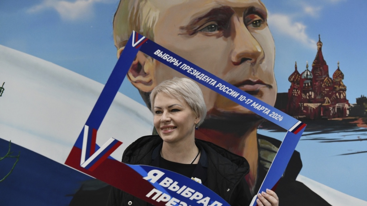 A woman poses with a frame with the words reading "I've have chosen the president" after voting at a polling station.