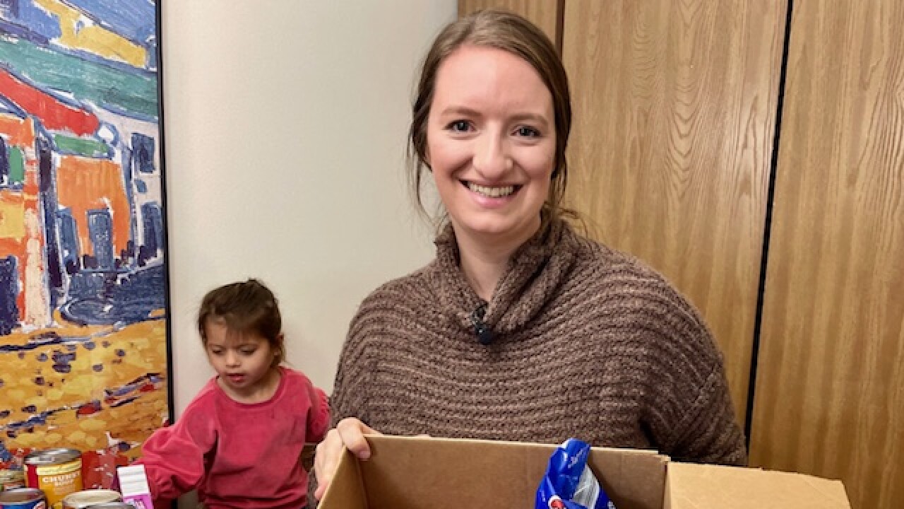 Rachel Hartberg holds a box of food she is packing from donations.