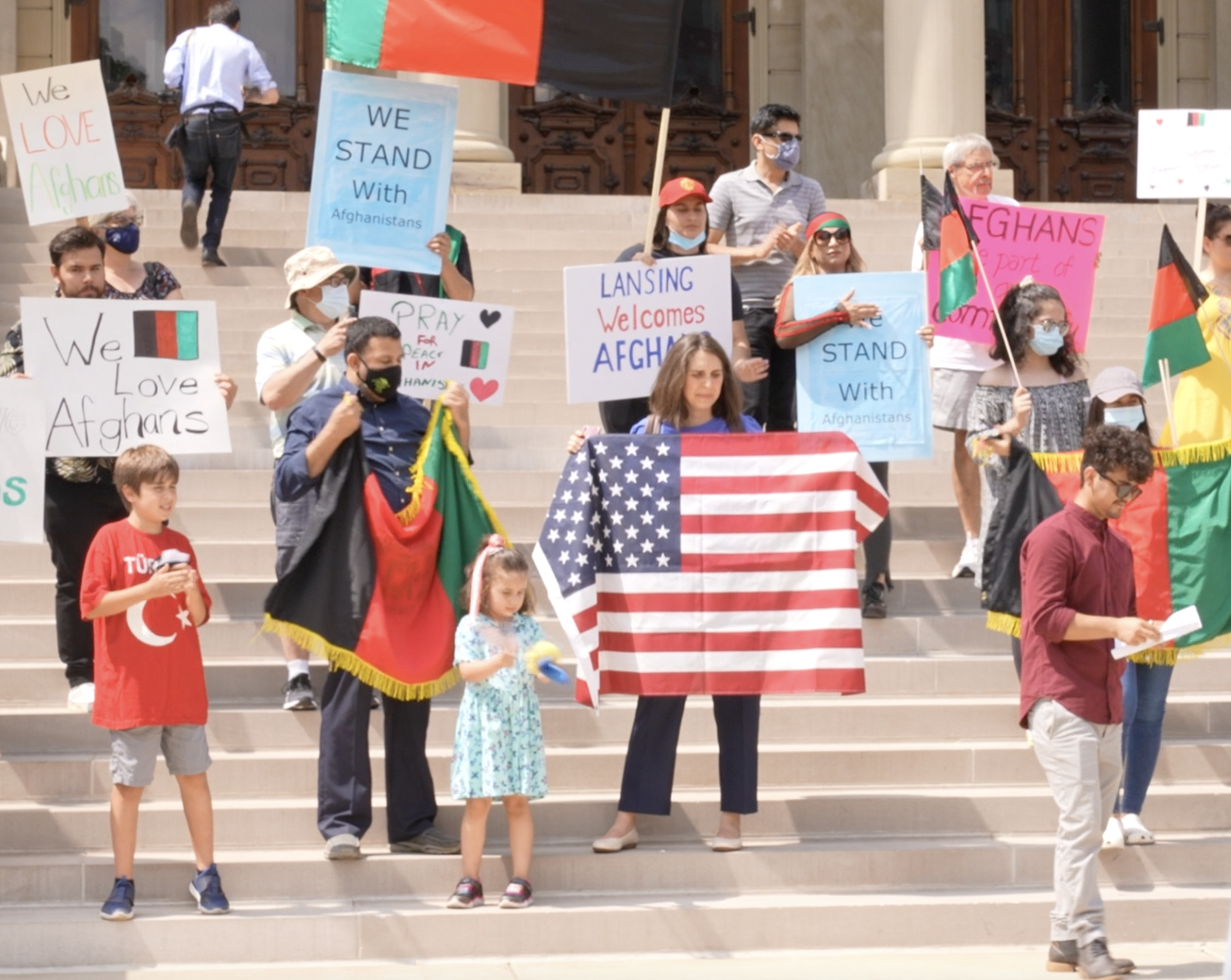 People standing on the steps of the capitol, holding signs. 