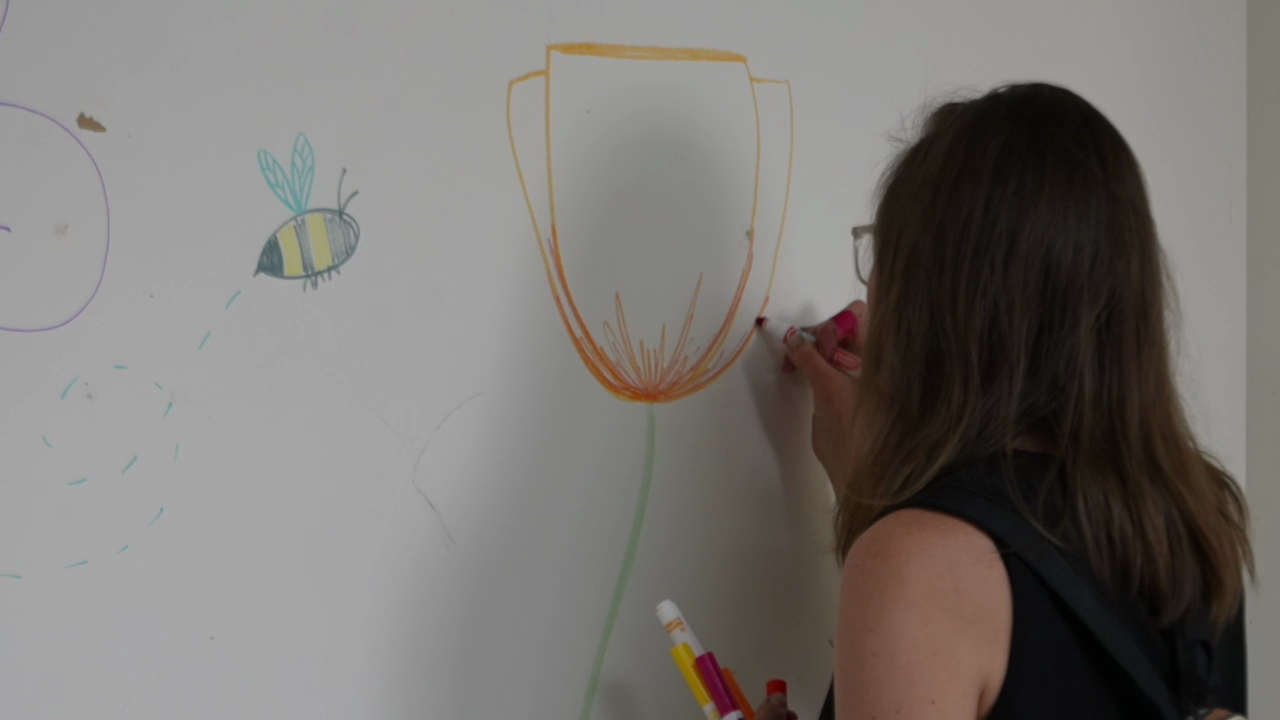 A neighbor draws on the wall at Sunday's event