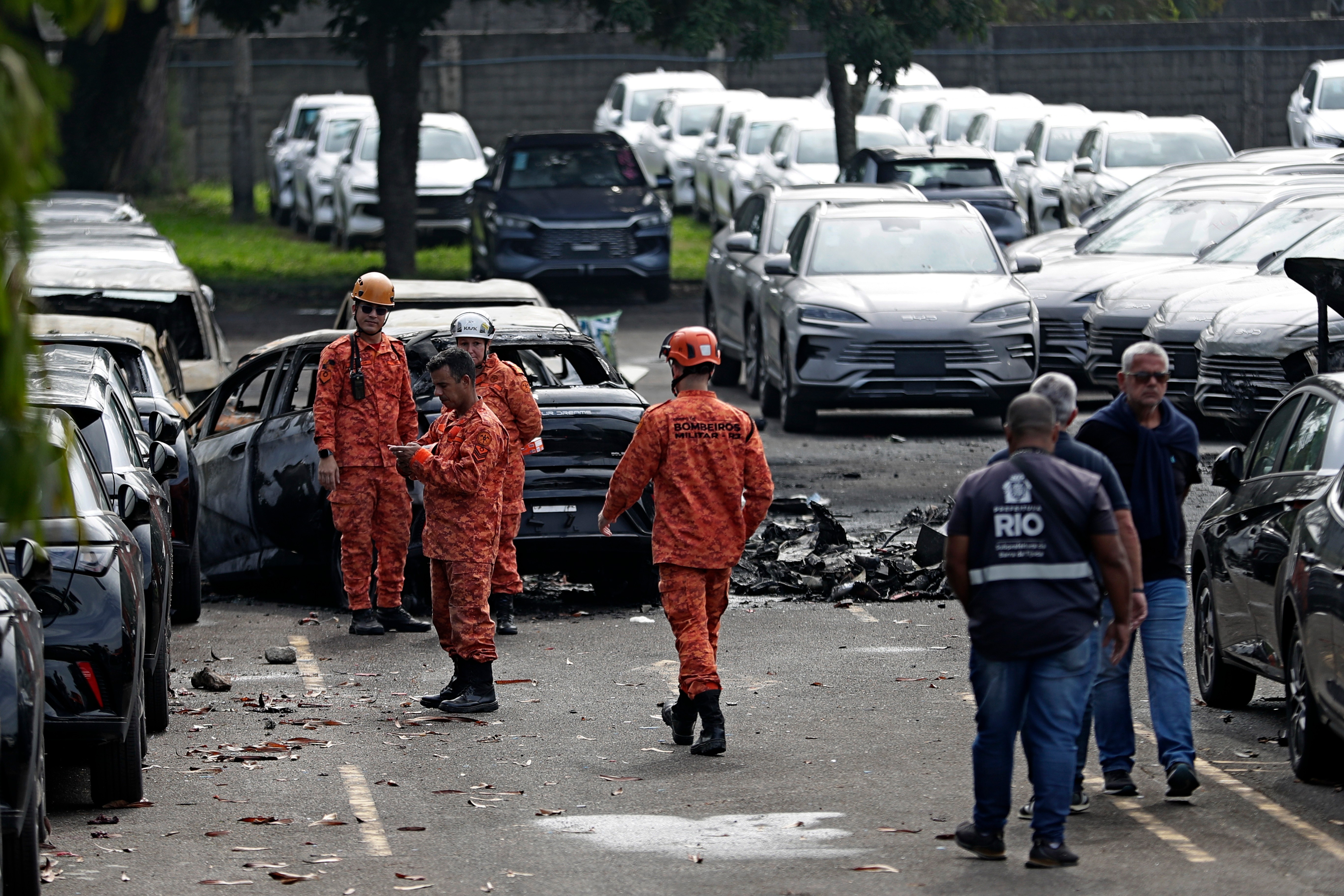 Emergency workers inspect the site where two helicopters reportedly collided in midair and crashed into a car dealership parking lot in Rio de Janeiro, Brazil, Sunday, June 14, 2026.