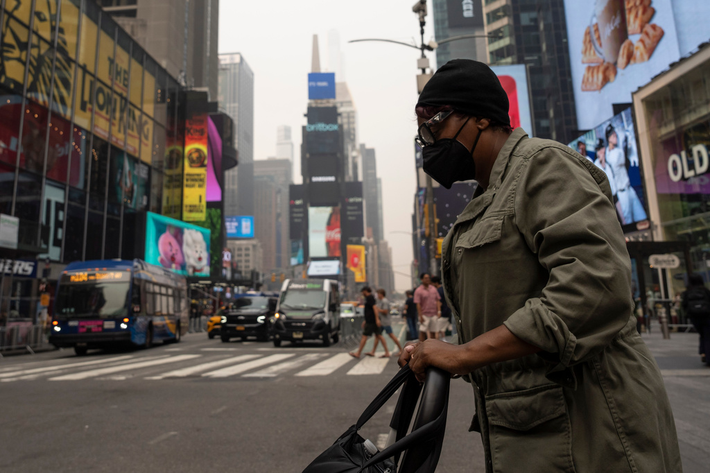 A person wearing a mask walks in Times Square as smoke from wildfires blankets the sky, Thursday, July 16, 2026, in New York. 