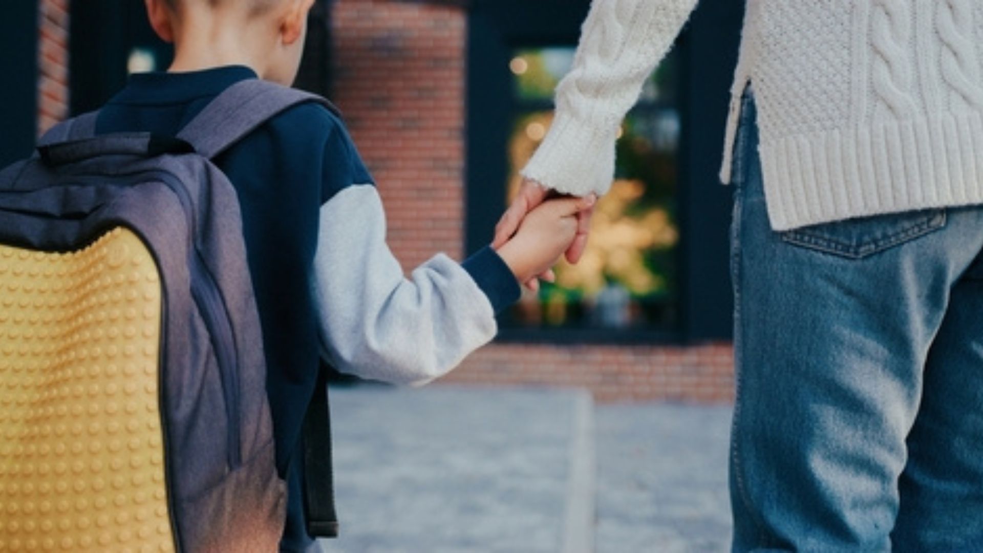 Stock image of a young boy and his mother holding hands.