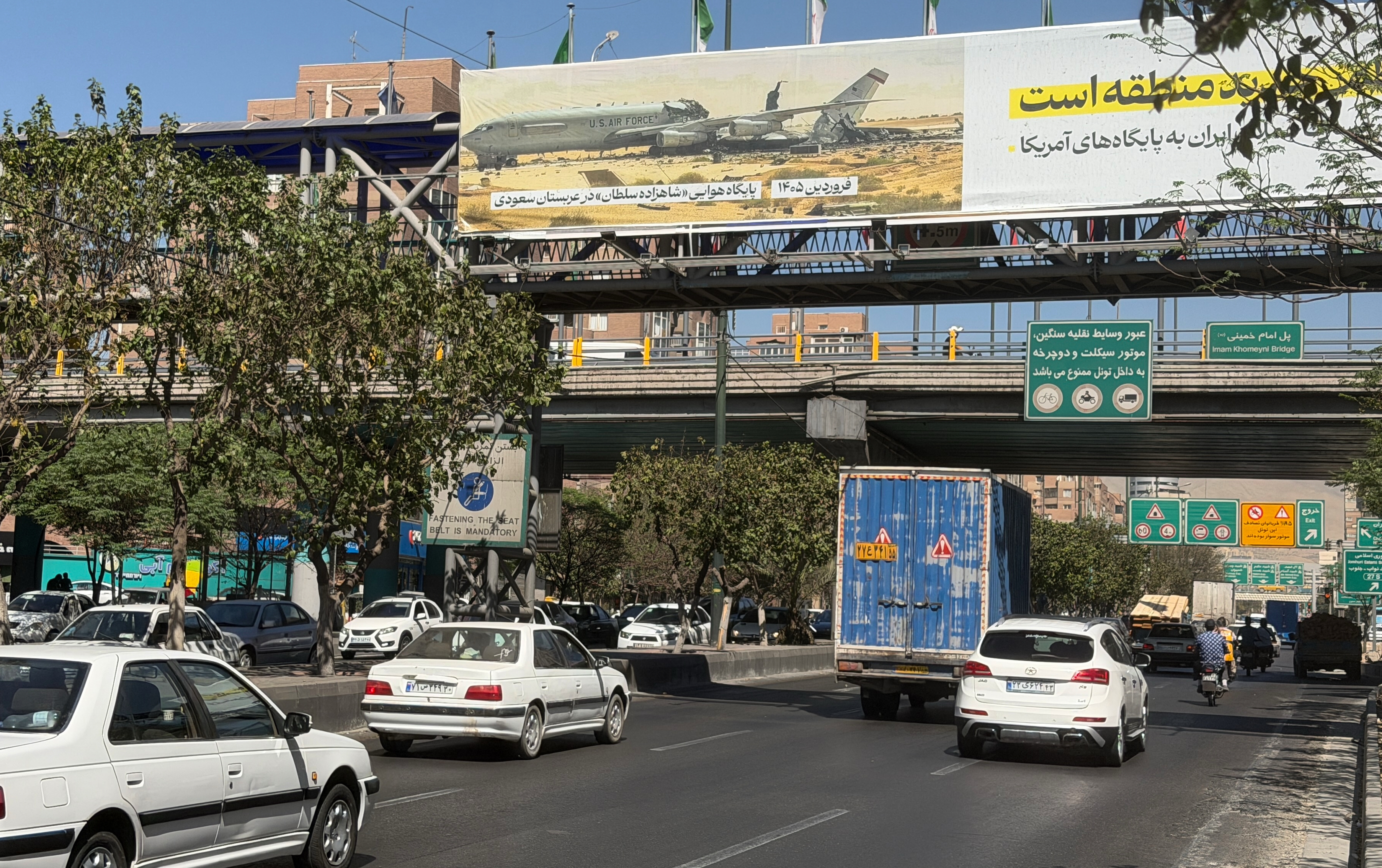 Vehicles travel beneath a billboard depicting a wrecked U.S. Air Force aircraft, with Persian writing identifying the location as Prince Sultan Air Base in Saudi Arabia, along a highway in Tehran, Iran, Wednesday, Sept. 23, 2026. 