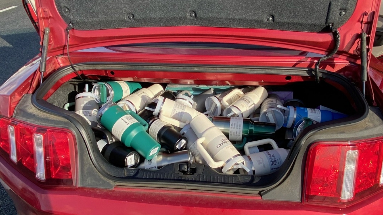 Trunk of a red car filled with Stanley "quencher" tumblers.