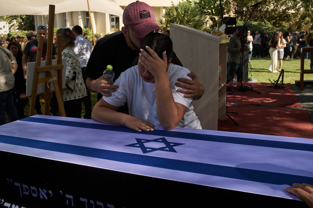Yuval, right, and Tom mourn over the coffin of their father, the slain hostage Ronen Engel, after his body was returned from Gaza as part of a ceasefire agreement between Israel and Hamas, during his funeral at Kibbutz Nir Oz, southern Israel, Tuesday, Oct. 21, 2025. 