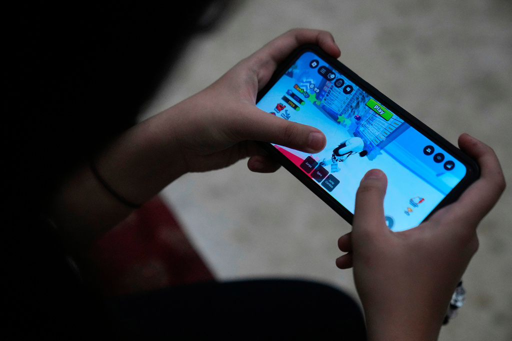 FILE - A person plays Roblox on a mobile phone.
