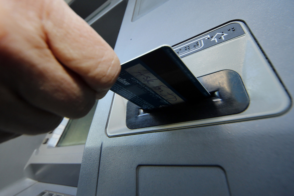 A person inserts a debit card into an ATM in Pittsburgh. 