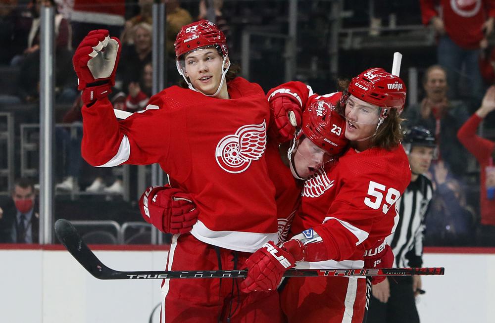 Detroit Red Wings left wing Lucas Raymond (23) celebrates with defenseman Moritz Seider (53) and left wing Tyler Bertuzzi (59) 