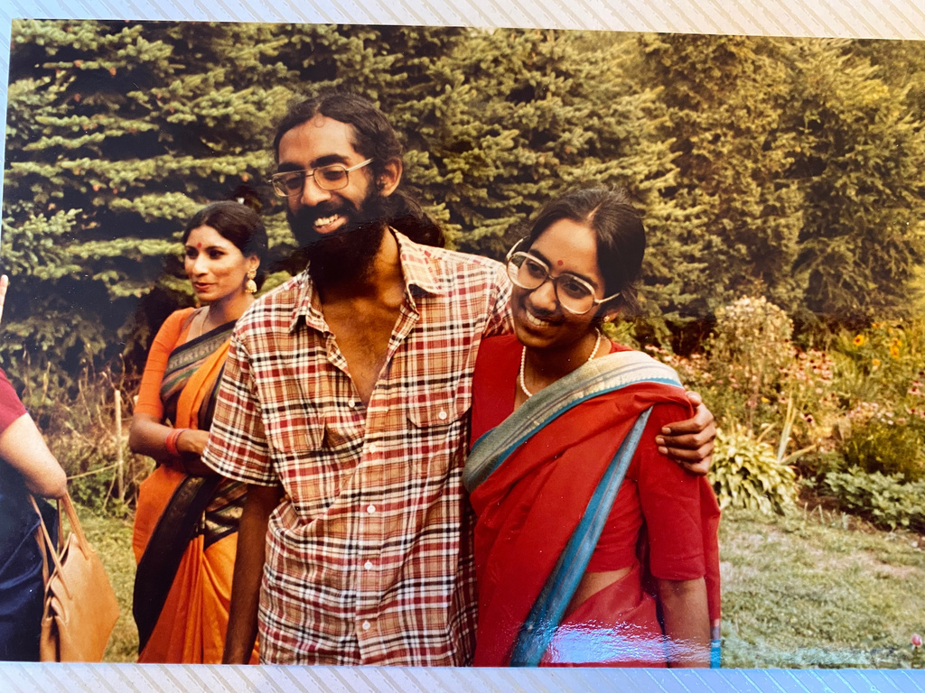 Tejaswini Rao chats with party guests while Subramanyam and Saraswathi Vedam embrace during their parents' wedding anniversary party at State College, Pa., in August 1981.