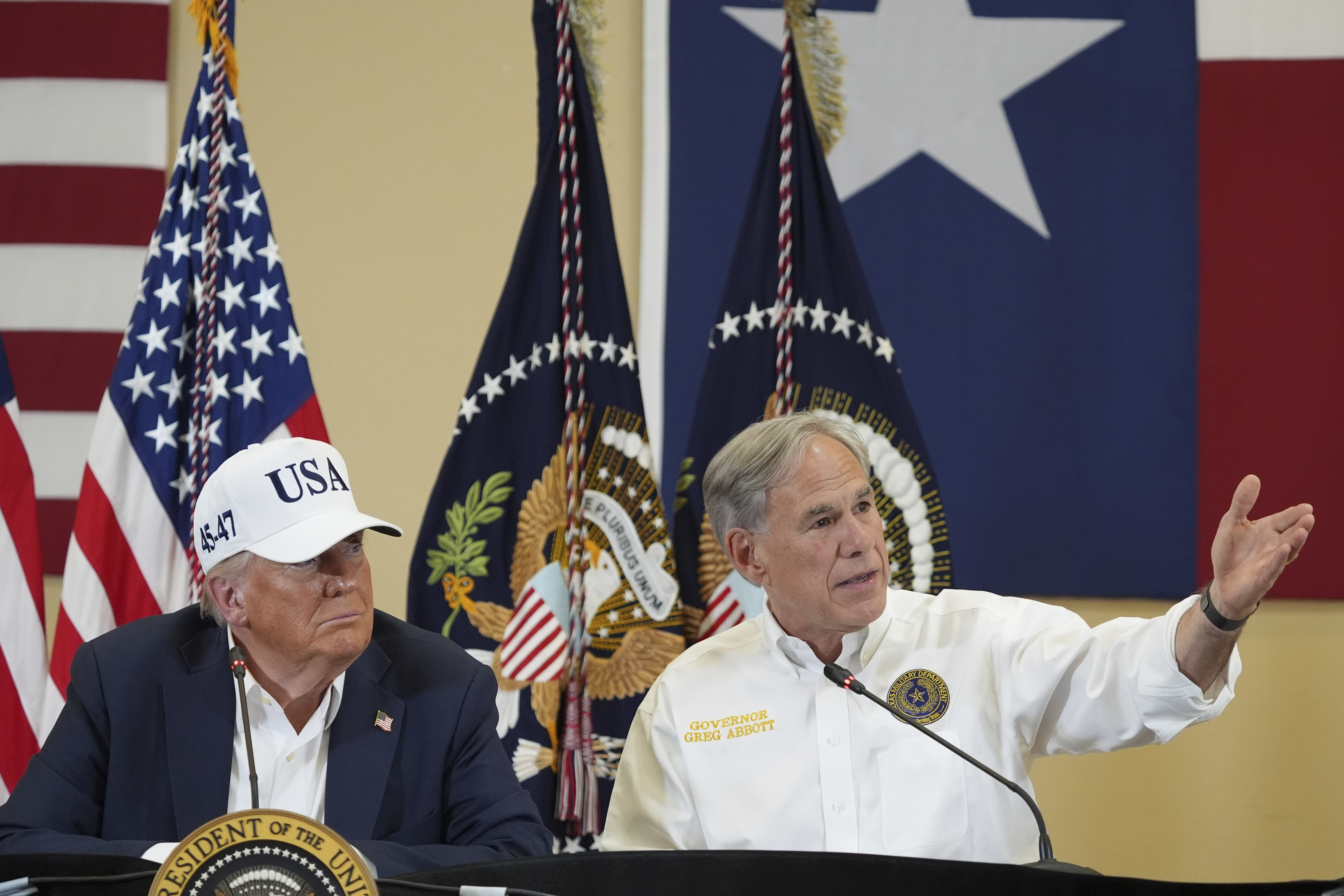 Texas Gov. Greg Abbott speaks as President Donald Trump listens during a roundtable discussion with first responders and local officials at Hill Country Youth Event Center in Kerrville, Texas, during a tour to observe flood damage, Friday, July 11, 2025. 