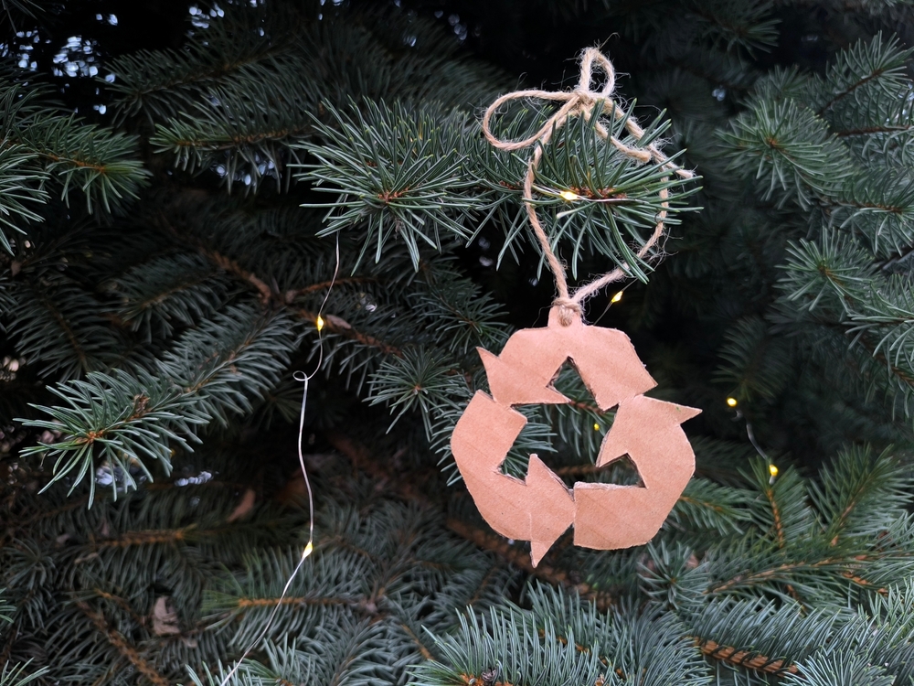 A recycle logo ornament on a Christmas tree.