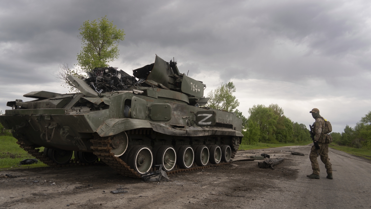 Ukrainian serviceman walks past a blown Russian APC in east Ukraine