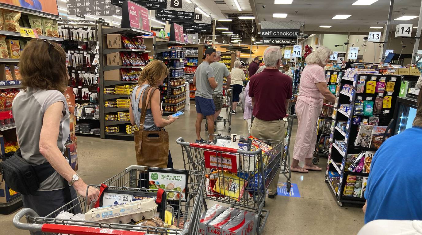 FILE IMAGE:  shoppers queue up in long lines to check out their items at a grocery store. 
