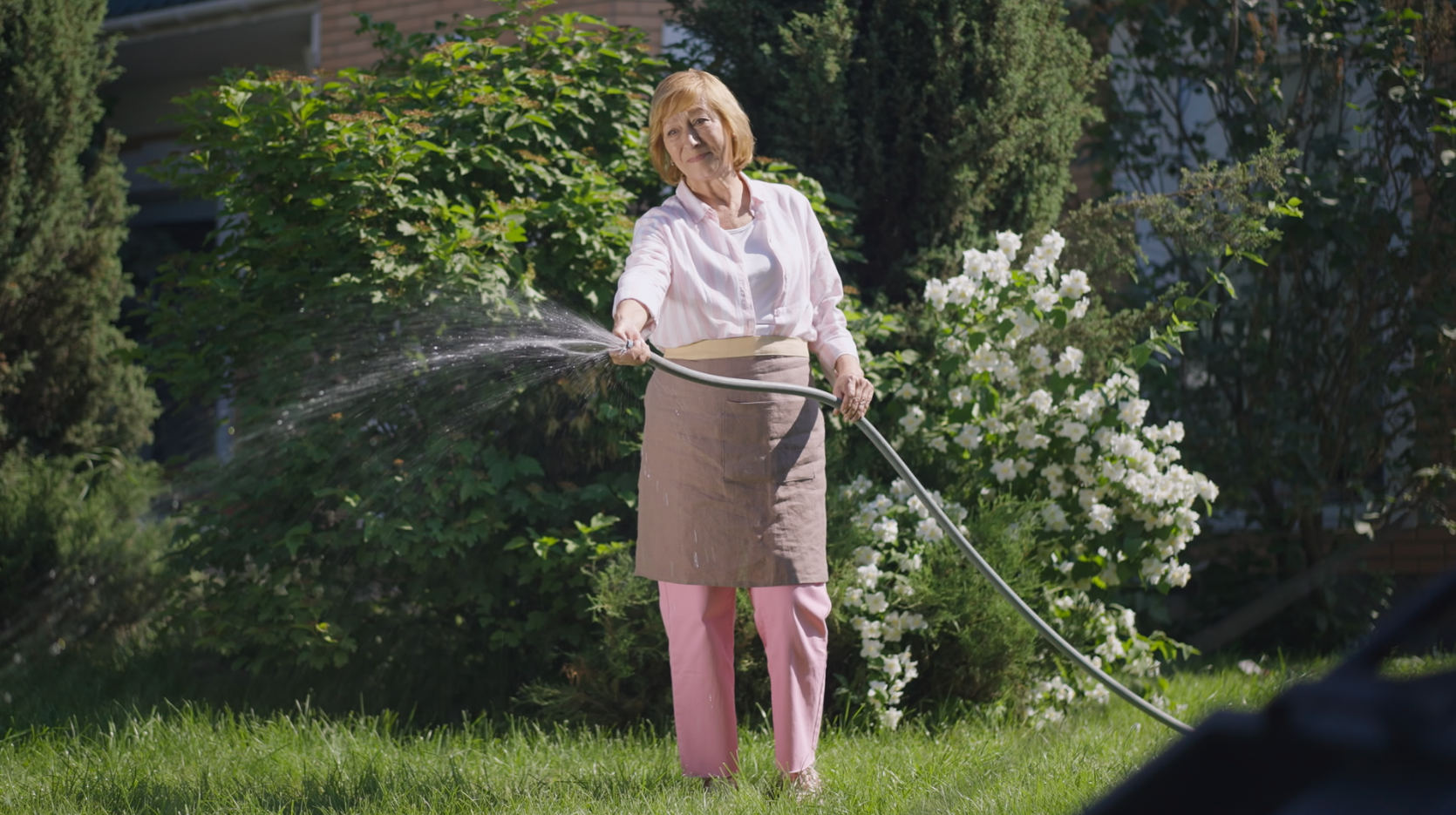 woman watering garden with a hose