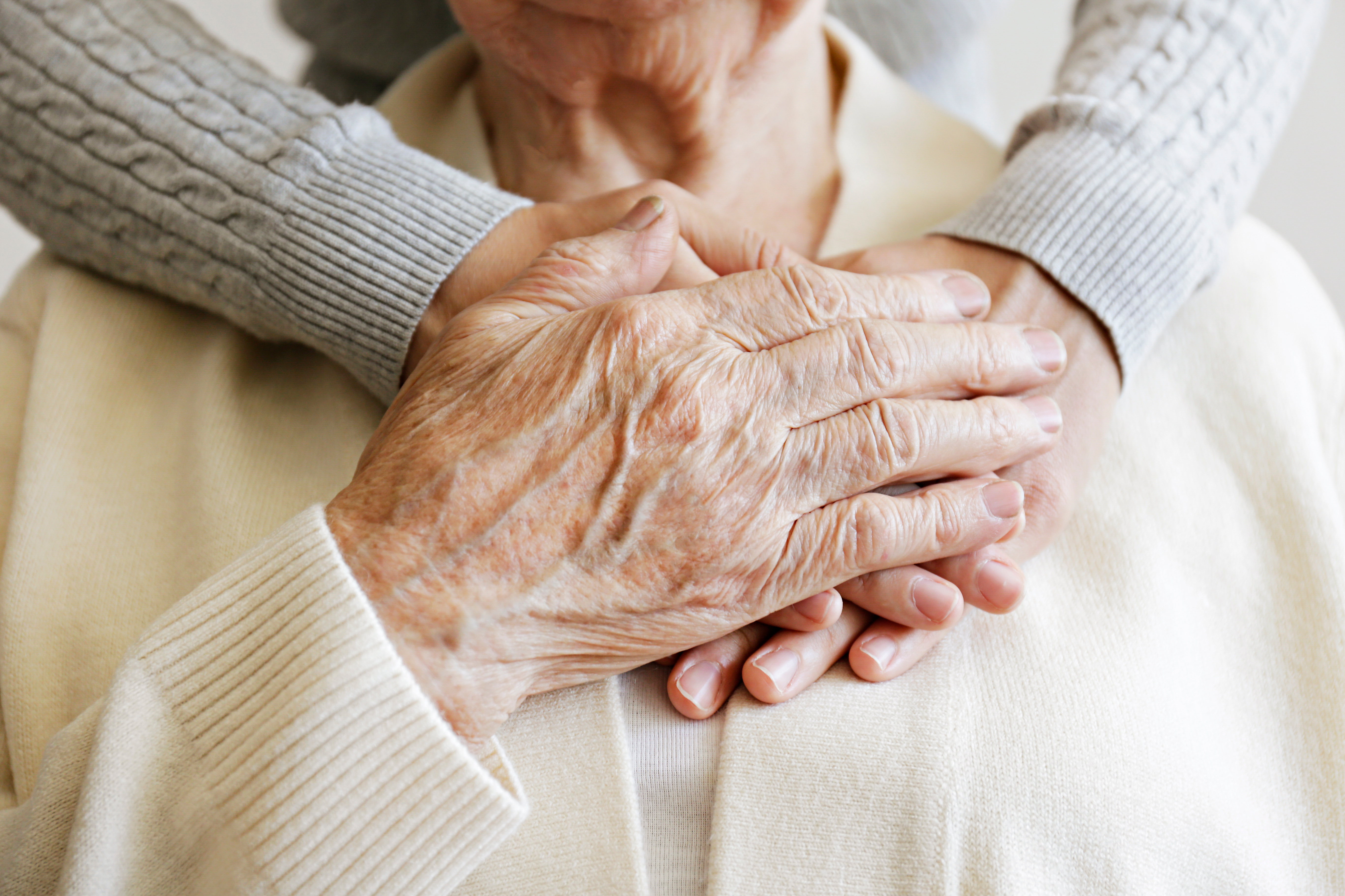 Mature female in elderly care facility gets help from hospital personnel nurse.