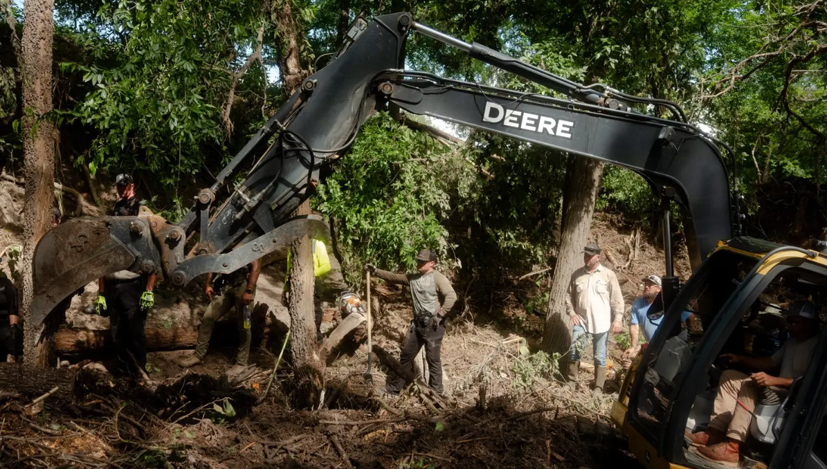 Law enforcement officials and volunteers clear up mountains of debris deposited by the flood in Center Point on Tuesday, July 8, 2025.