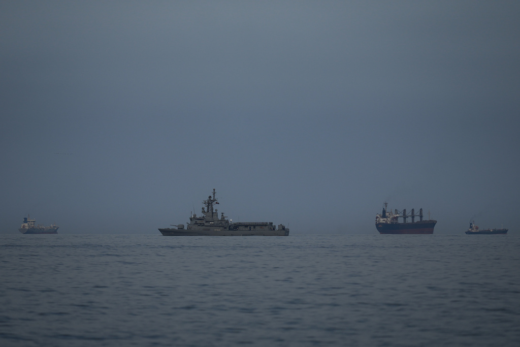 A UAE navy vessel patrols next to cargo ships and oil tankers in the Strait of Hormuz as seen from Khor Fakkan, United Arab Emirates, Wednesday, March 11, 2026.