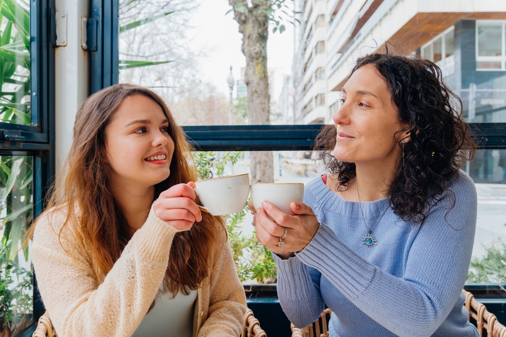 Mother and daughter sipping a drink.