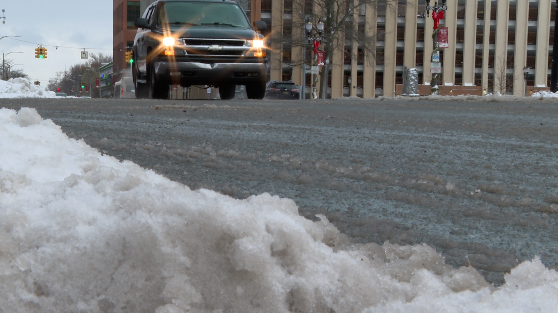 Car drives north on Capitol Avenue in Lansing with slushy snow in foreground