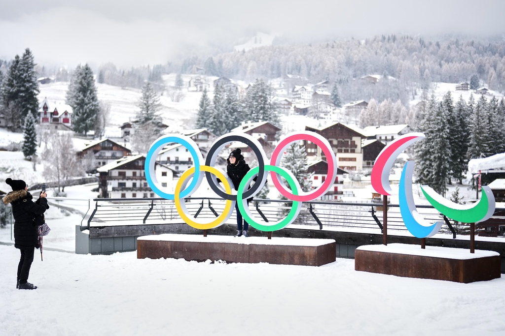 People take photos in front of the Milan Cortina Winter Olympics and Paralympics rings, in Cortina D'Ampezzo.