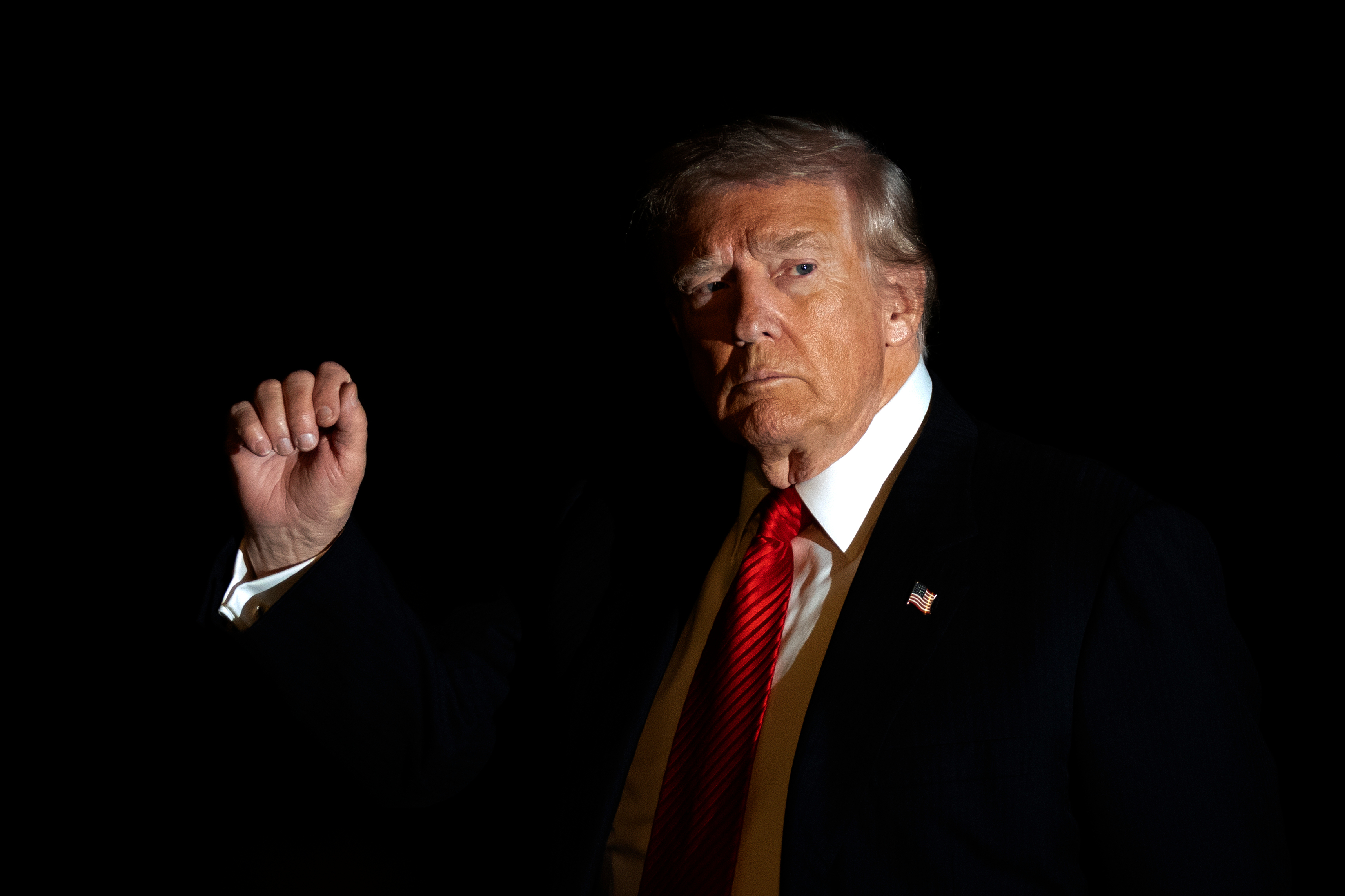 President Donald Trump is illuminated by a camera flash as he gestures while walking across the South Lawn of the White House, Sunday, Nov. 2, 2025, in Washington, after returning from a trip to Florida. 