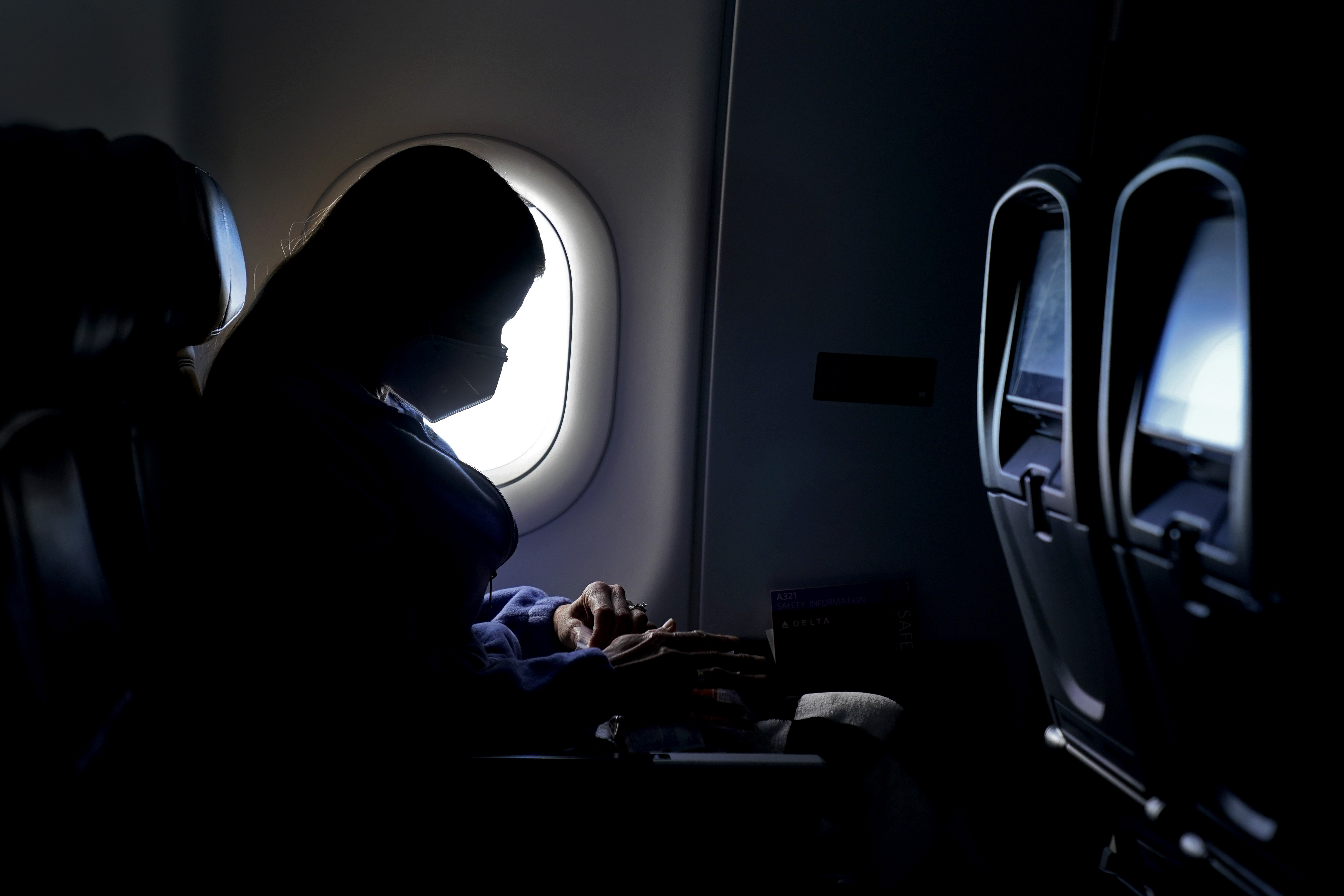 woman wears mask on plane in Atlanta, Feb. 3, 2021