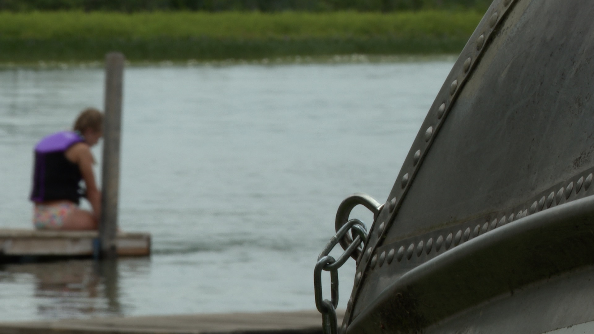 Boat locked with girl sitting on a dock at Portage Lake in Jackson County