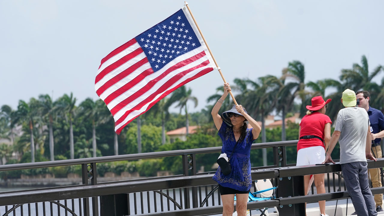Adriane Shochet stands on a bridge outside the entrance to former President Donald Trump's Mar-a-Lago estate, Tuesday, Aug. 9, 2022, in Palm Beach, Fla. 