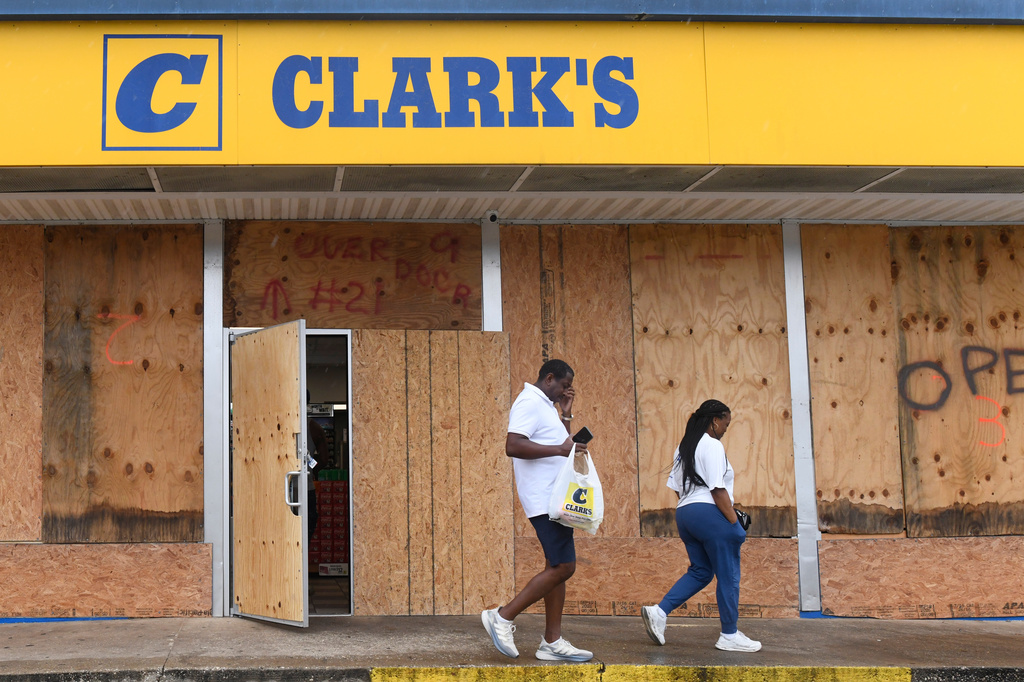 People walk out of a boarded up gas station in preparation for Isaias on Friday, Oct. 9, 2026, in downtown Mobile, Ala. 