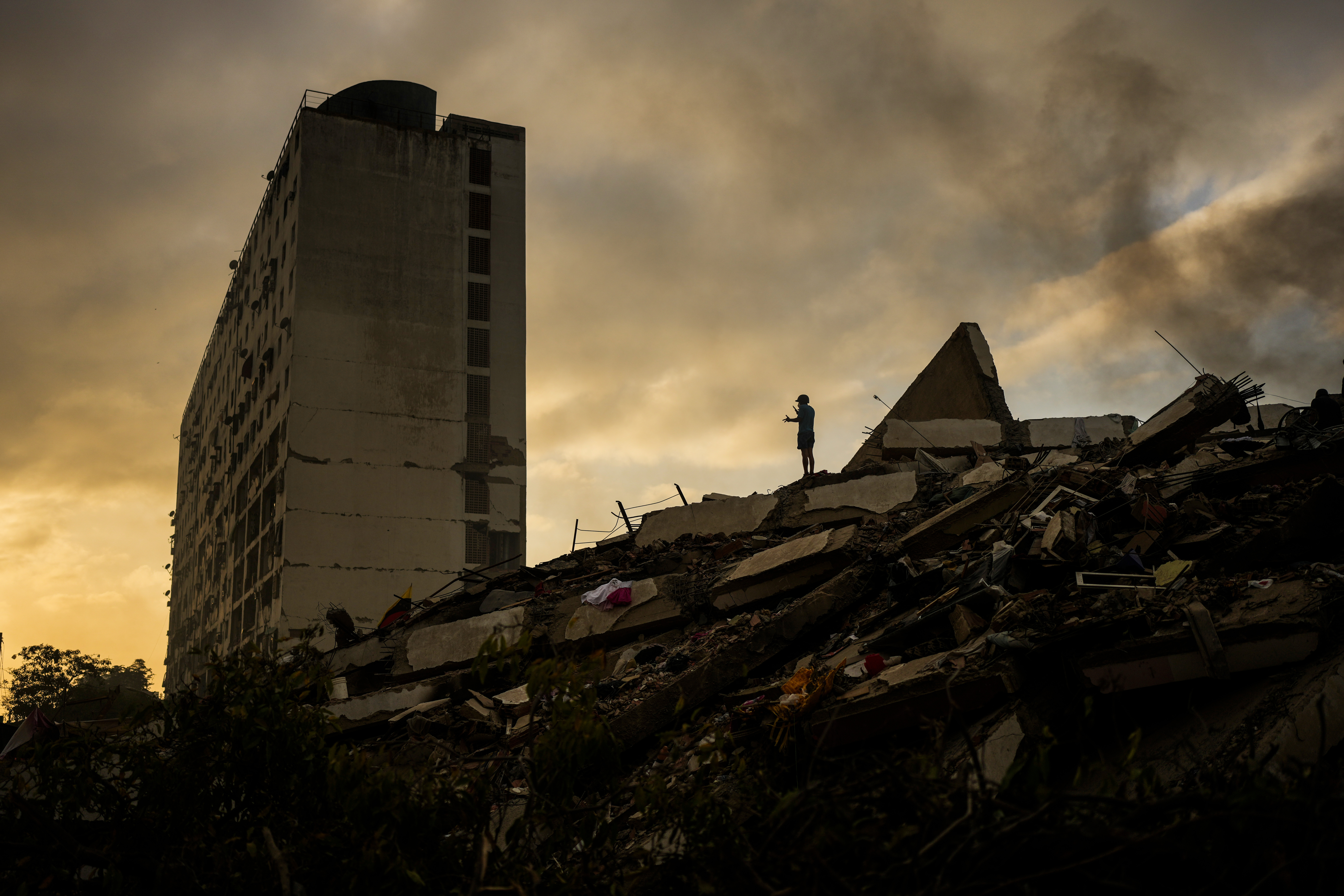 A man stands atop a mountain of rubble three days after twin earthquakes struck, in La Guaira, Venezuela, Saturday, June 27, 2026.