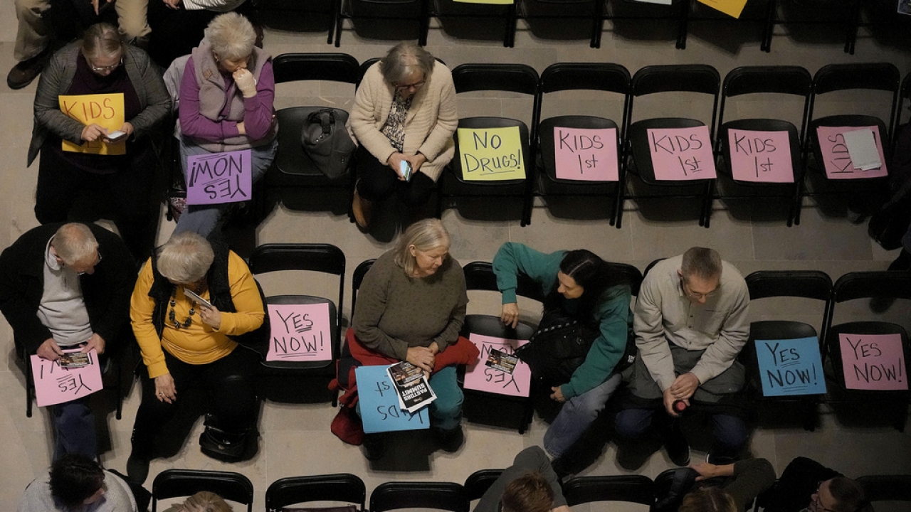 People wait for the start of a rally in favor of legislation banning gender-affirming care