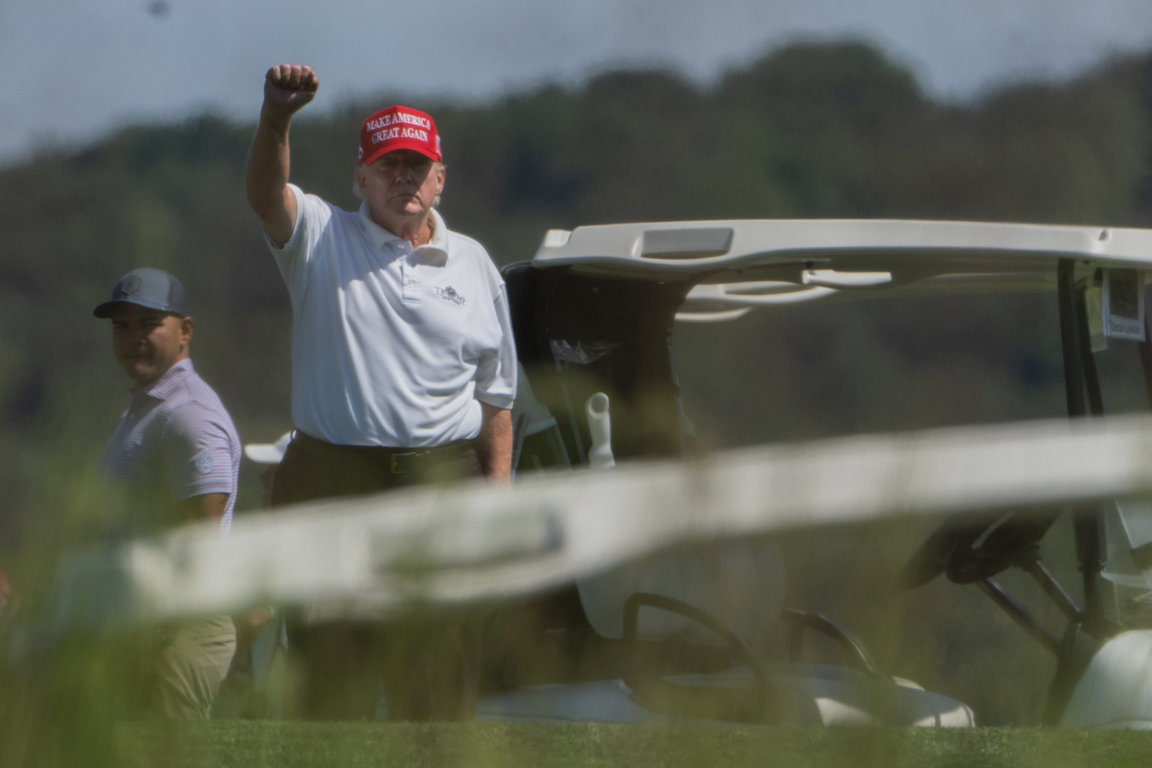 Donald Trump wearing 'Make America Great Again' hat holds out fist while golfing in Virginia