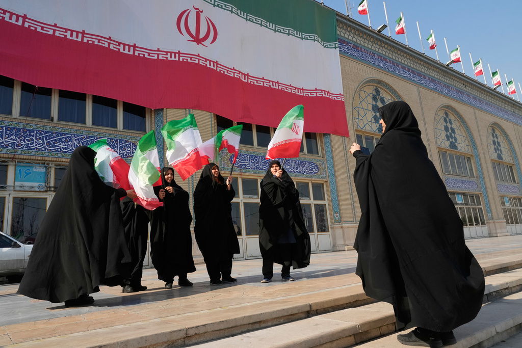 Women with Iranian flags take a group photo during a state-organized memorial ceremony for those killed during January's anti-government protests, at the Imam Khomeini Grand Mosque in Tehran, Iran, Tuesday, Feb. 17, 2026.