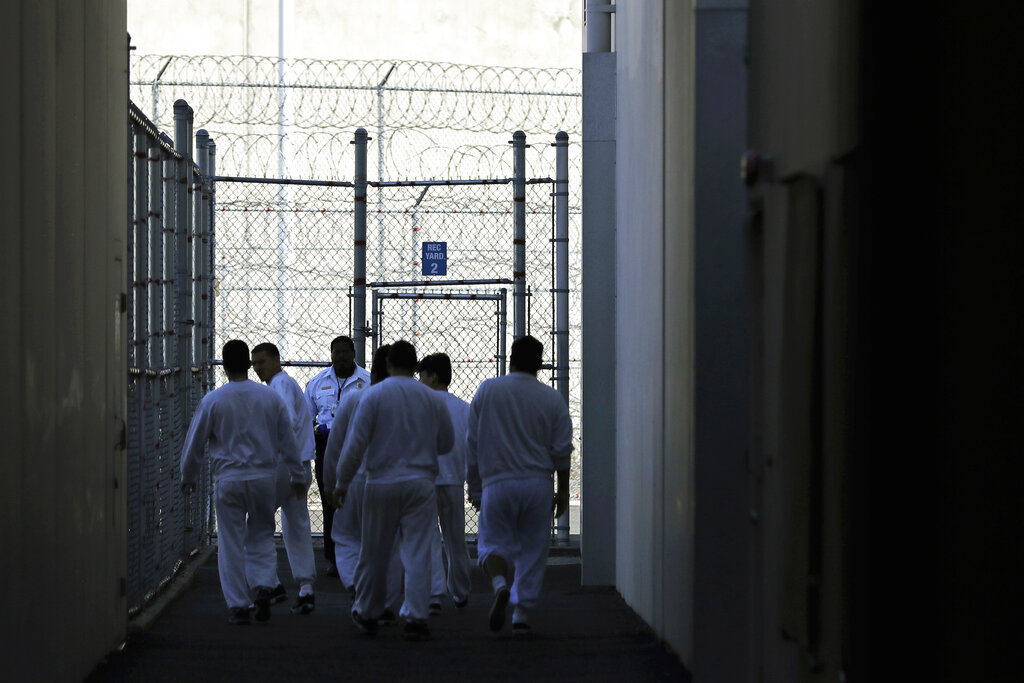 In this photo taken Sept. 10, 2019, detainees walk toward a fenced recreation area at the GEO Group’s immigration jail in Tacoma, Wash.
