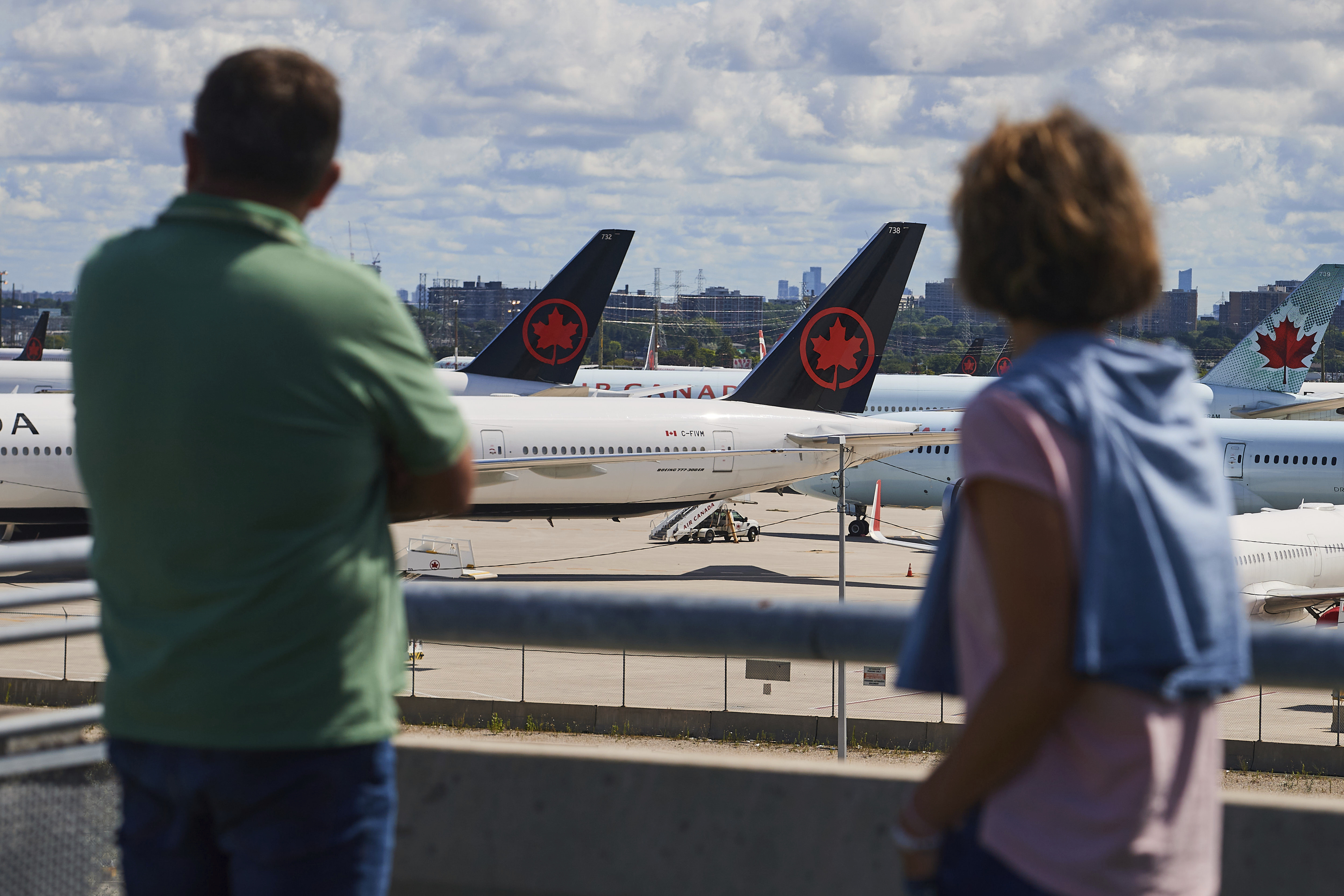 Travelers look out over grounded Air Canada planes as flight attendants picket at Pearson International Airport in Toronto, Monday, Aug. 18, 2025. 