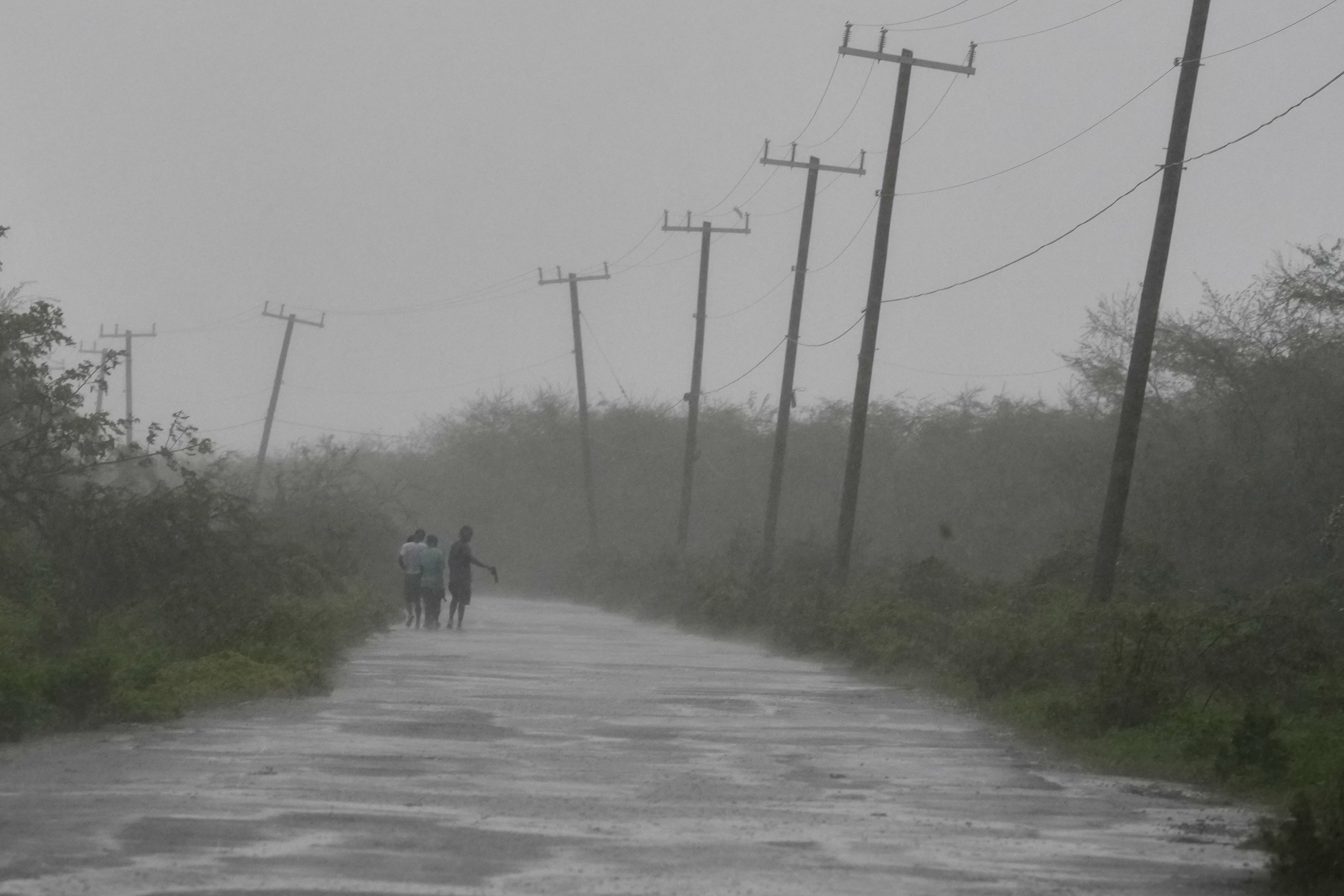 People walk along a road during the passing of Hurricane Melissa in Rocky Point, Jamaica, Tuesday, Oct. 28, 2025.