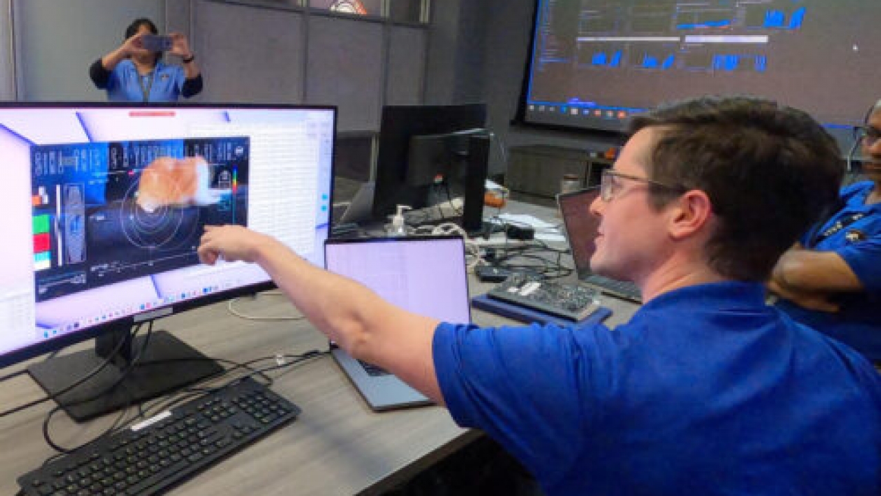Members of NASA's Deep Space Optical Communications reaction to video on a computer screen.