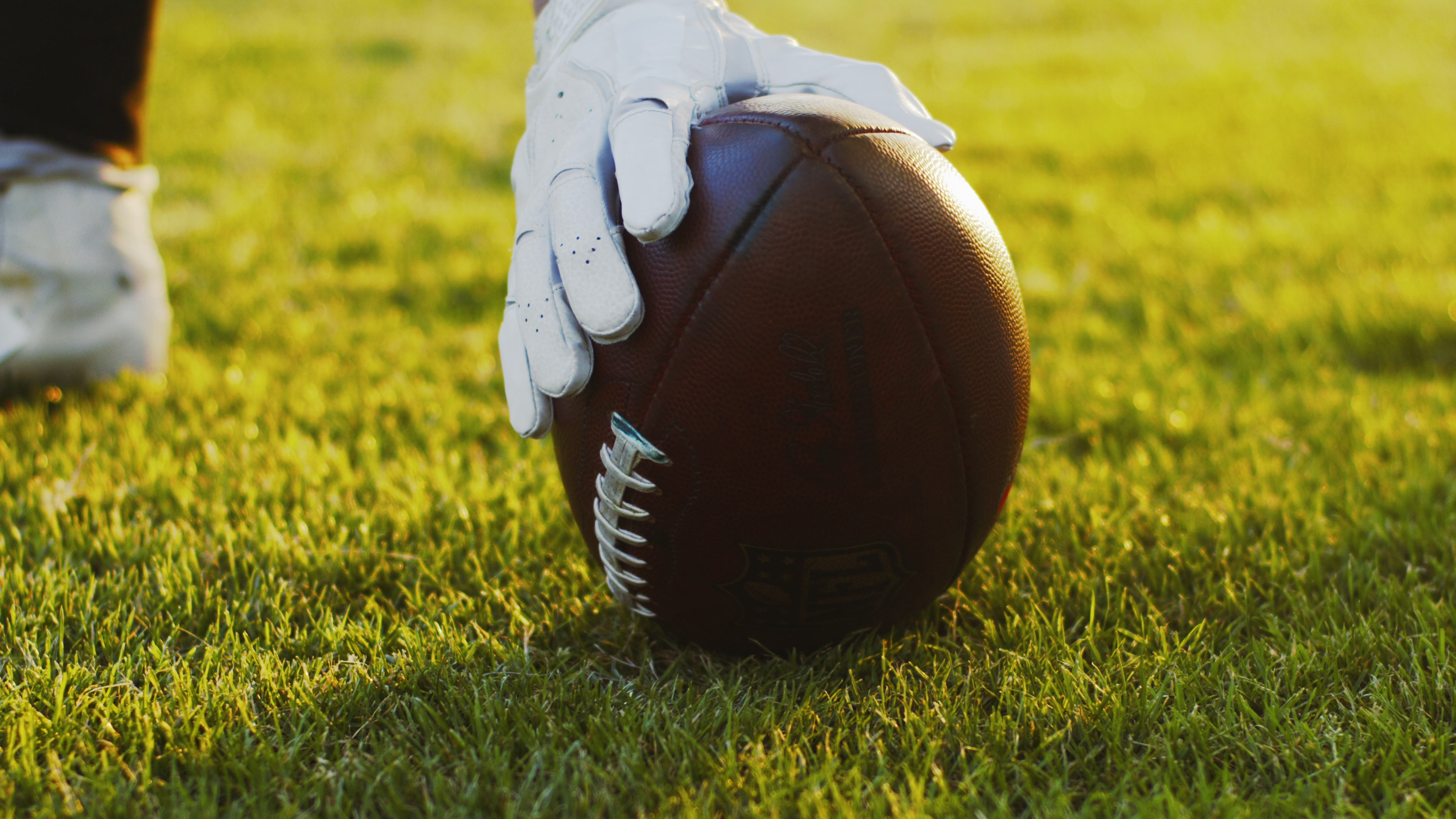 cropped-view-of-the-american-football-player-wearing-gloves-taking-ball-from-the-field-SBI-350746043.jpg