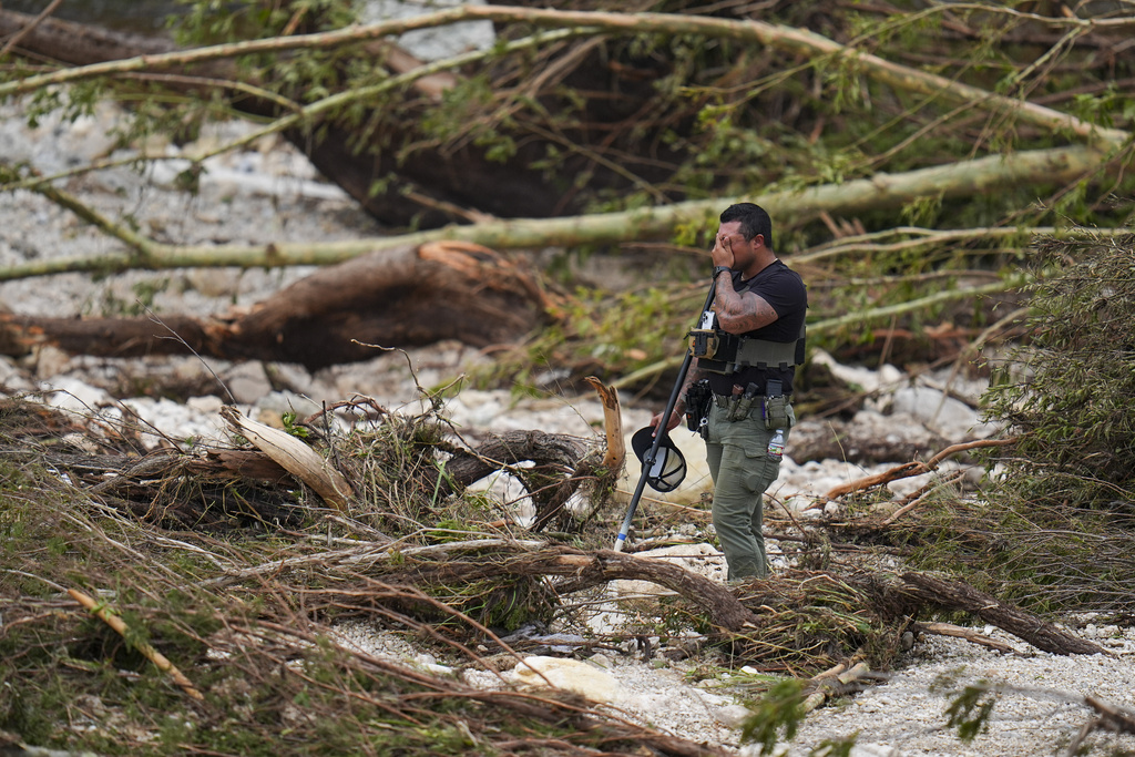 File photo of a sheriff's deputy combing through debris on the banks of the Guadalupe River near Camp Mystic in Hunt, Texas.