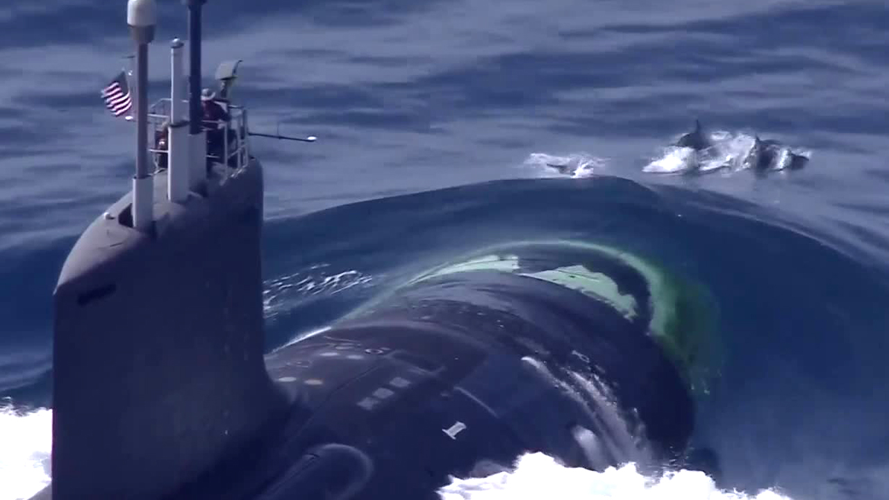 A pod of dolphins was spotted frolicking alongside a U.S. submarine off the South Florida coast on June 24, 2020. 