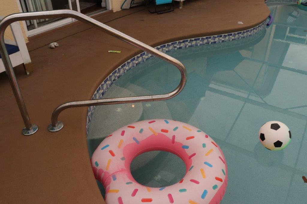 A pool with a ring and a soccer ball. 