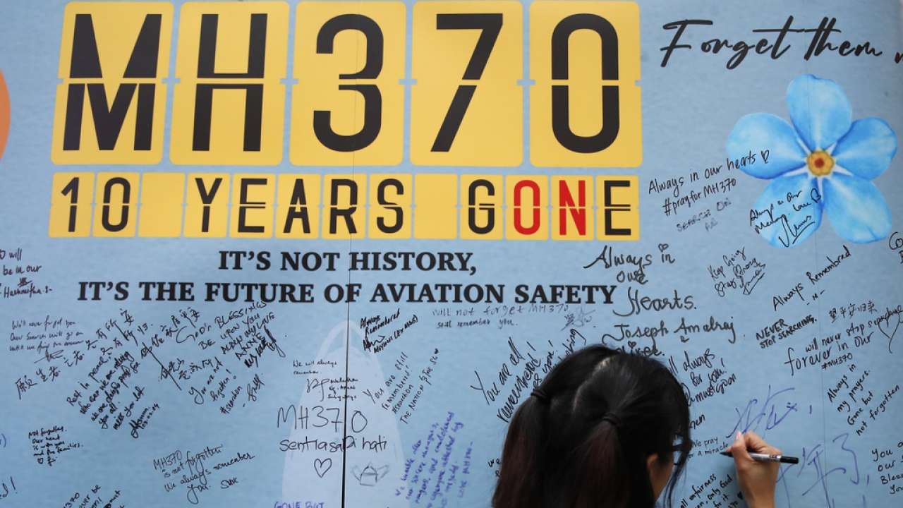 A woman writes well messages on a message board during a remembrance event for MH370.