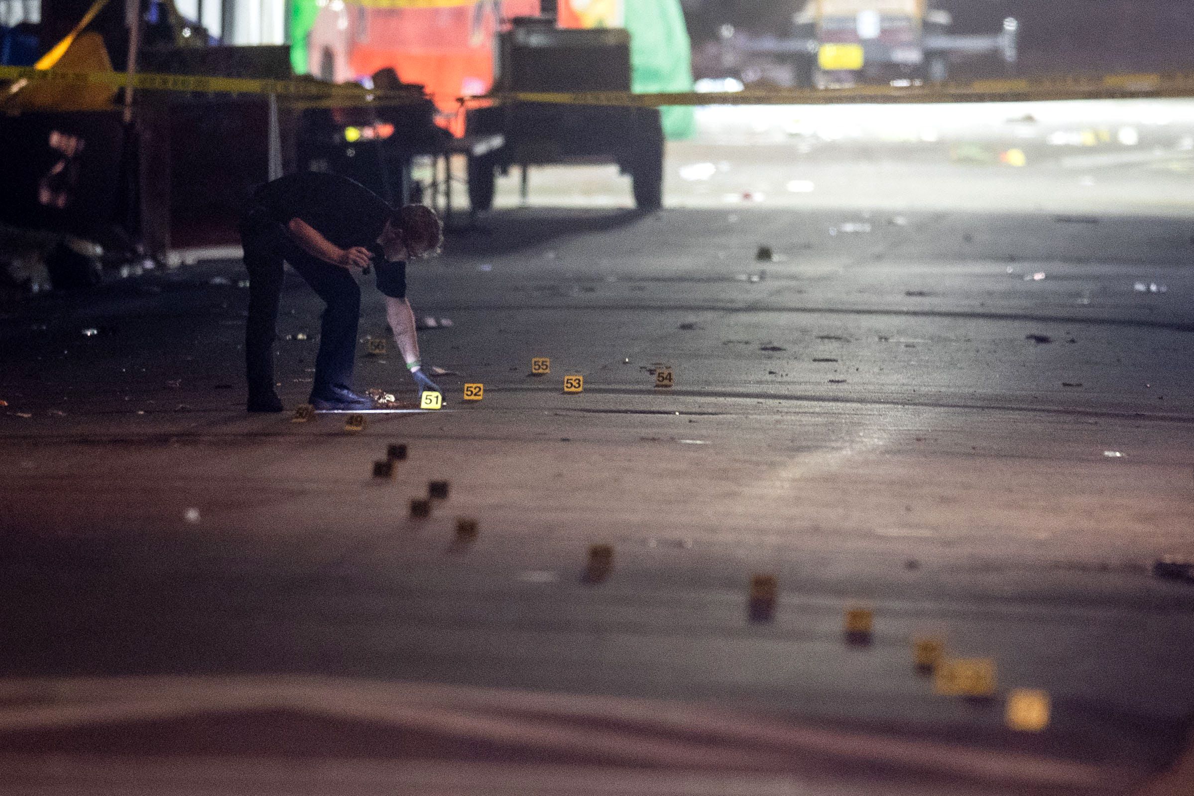 An investigator with the Tallahassee Police Department uses a flashlight to look over dozens of evidence markers that snaked down Perry Street behind Florida A&M University's Bragg Memorial Stadium as police investigate a mass shooting Saturday, October 24, 2026.